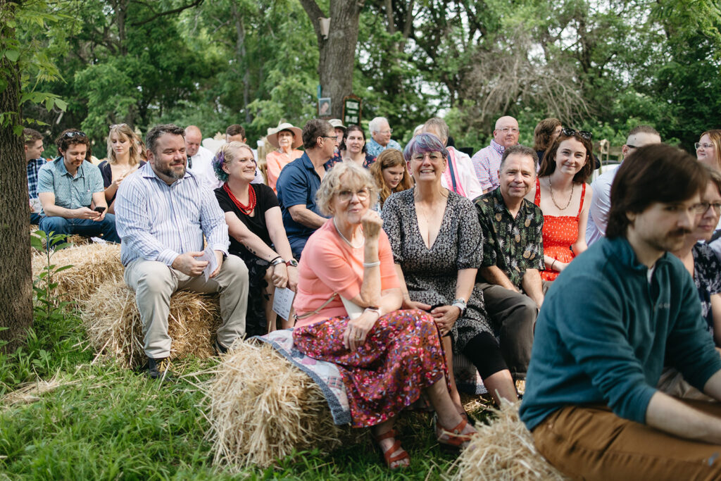 Family members seated on hay bales in the front yard before the wedding ceremony begins.